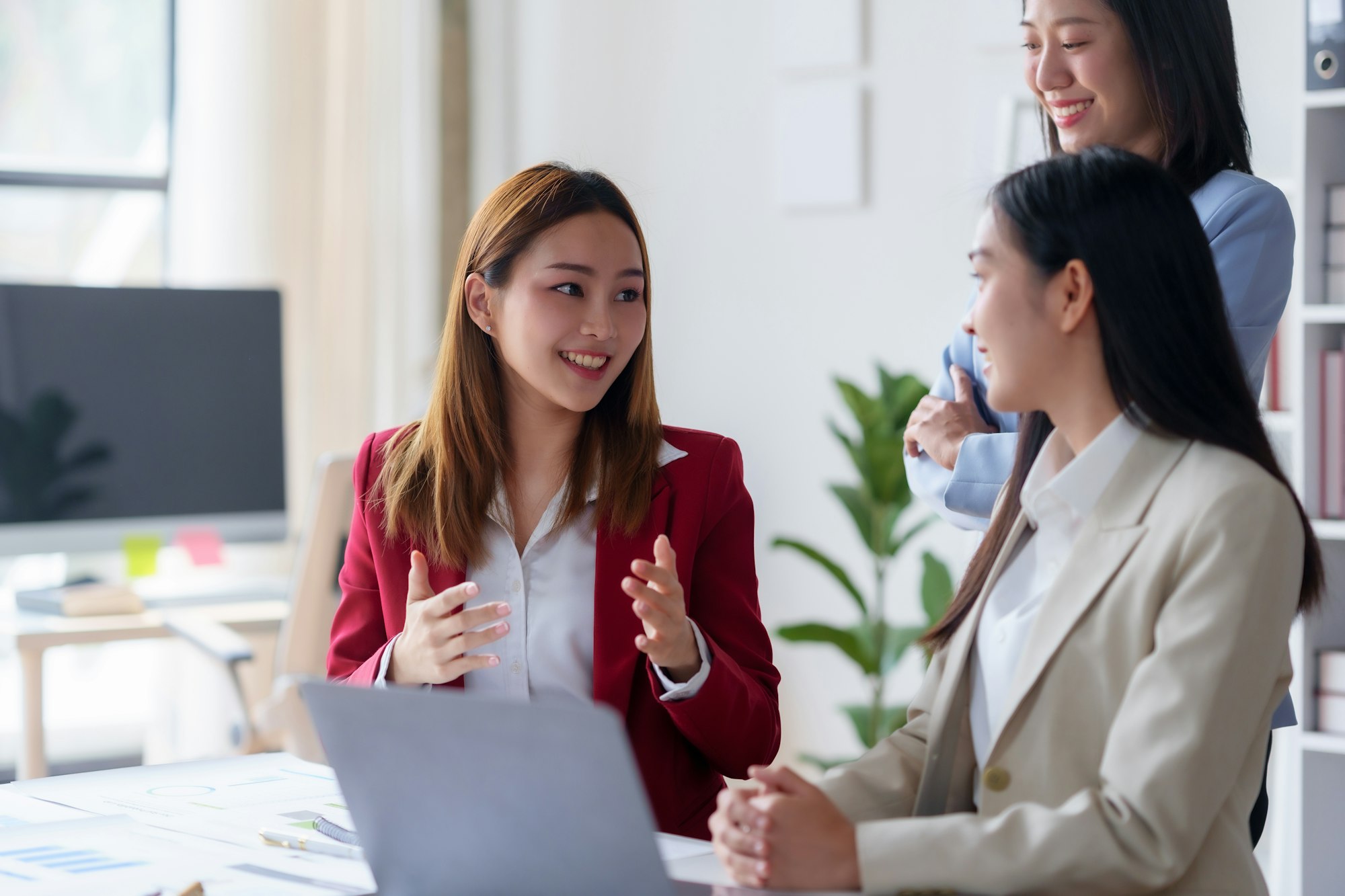 Three young businesswomen collaborate on a project in a modern office