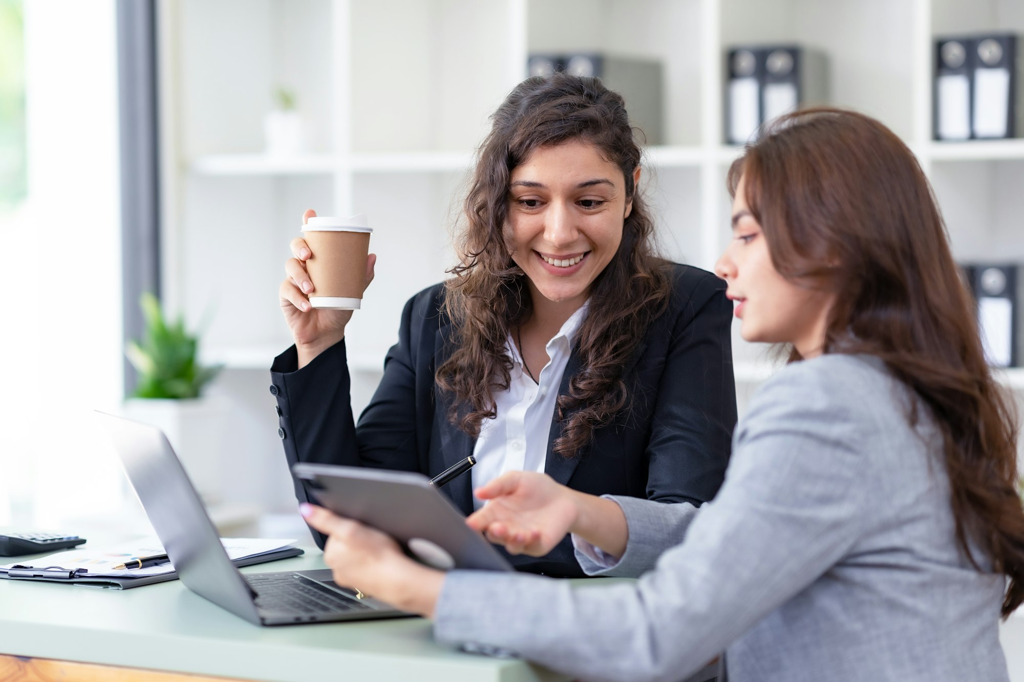 Two businesswomen discussing work and solutions from work using laptop computer for work.