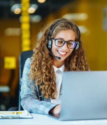 Call center agent with headset working on support hotline in modern office. Video conference.